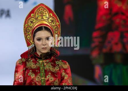 Moskau, Russland. 26. März 2023. Ein Modell präsentiert traditionelle russische Nationalkostüme auf einem Laufsteg als Teil der Show „Edges of the World“ beim Kids Fashion Week Kindermodefestival im Central Children's Store auf Lubjanka in Moskau, Russland Stockfoto