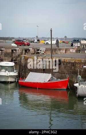 Ein hölzernes Segelboot wird angedockt, sein Deck ist geschützt. Vor und hinter ihm sind andere Boote. Stockfoto