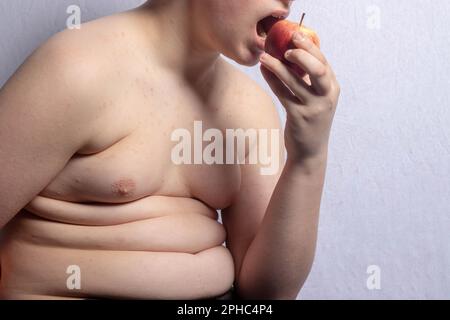 Ein übergewichtiger, weißer Teenager, der Apfel isst Stockfoto