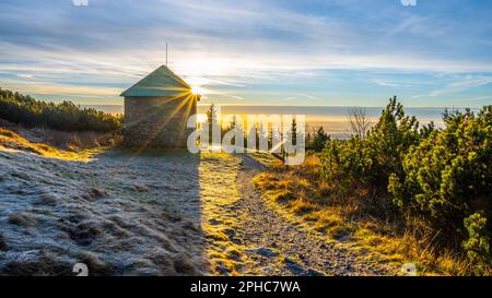 Ein frostiger, sonniger Morgen mit Sonnenstrahlen, die durch einen Steinunterschlupf im Jeleni studanka im Hruby-Jesenik-Gebirge in der Tschechischen Republik scheinen Stockfoto