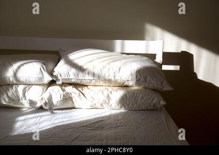 Ungemachtes Bett, beleuchtet von Morgensonne Stockfoto