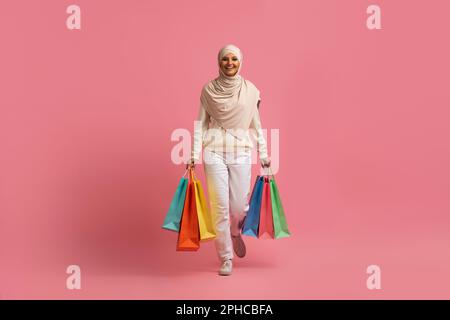 Wunderschöne Junge Muslimische Frau In Hijab, Die Mit Hellen Einkaufstaschen Spaziert Stockfoto
