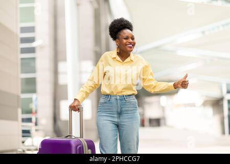 Afroamerikanische Touristenfrau, die ein Taxi in der Nähe des Flughafens anruft Stockfoto