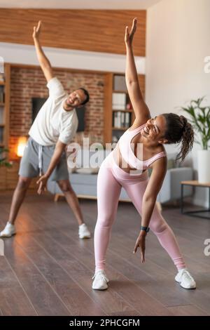Glückliche junge schwarze Sportlerinnen und Sportlerinnen machen zusammen Handübungen beim Workout Stockfoto