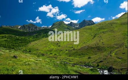 Berglandschaft im Frühling. Schöner, klarer Tag mit Bächen, die aus Bergen und grünen Hügeln fließen Stockfoto