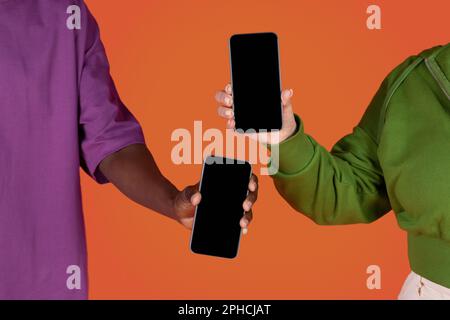 Ein Paar aus mehreren Rassen, das Telefone mit leeren Bildschirmen hält Stockfoto