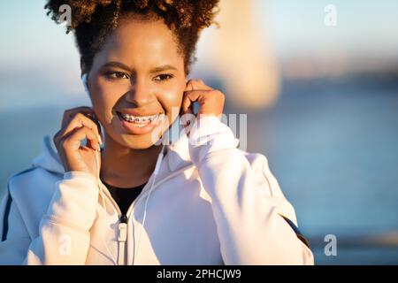 Lächelnde Junge Schwarze Mit Kopfhörern, Die Draußen Musik Hören Stockfoto