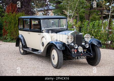 1932 Rolls-Royce 20/25 auf einer Schotterstraße mit Bäumen und Gärten in ländlicher Umgebung Stockfoto