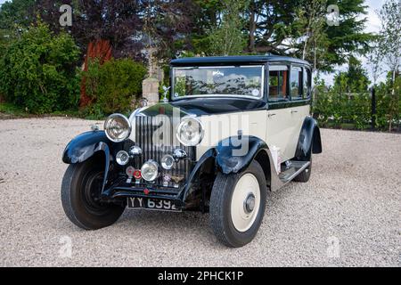 1932 Rolls-Royce 20/25 auf einer Schotterstraße mit Bäumen und Gärten in ländlicher Umgebung Stockfoto