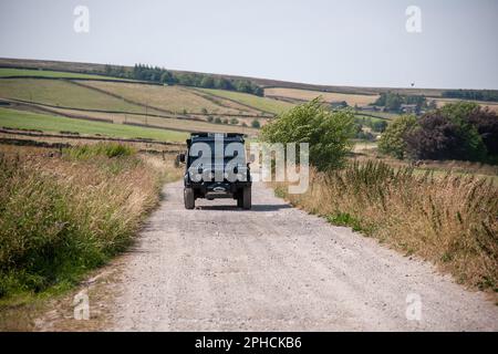 Black Land Rover Defender 110 mit langem Radstand an einem sonnigen Sommertag auf einer Kiesfarm in Yorkshire Stockfoto