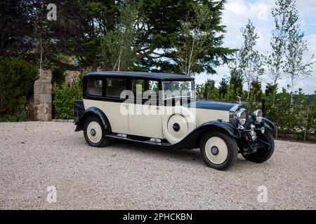 1932 Rolls-Royce 20/25 auf einer Schotterstraße mit Bäumen und Gärten in ländlicher Umgebung Stockfoto