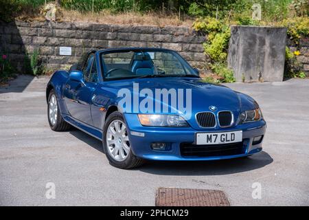 Der zweitürige Sportwagen BMW Z3 parkt an einem sonnigen Tag in einer Sackgasse mit einer Steinmauer und Hütten dahinter Stockfoto