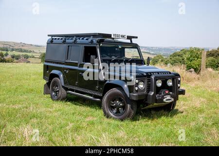 Der schwarze Land Rover Defender 110 mit langem Radstand parkt an einem sonnigen Sommertag auf einem Feld in Yorkshire Stockfoto