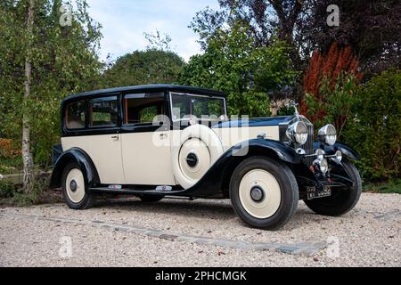 1932 Rolls-Royce 20/25 auf einer Schotterstraße mit Bäumen und Gärten in ländlicher Umgebung Stockfoto