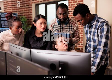 Vielfältiges Team von Systemingenieuren analysiert HTML-Skriptinformationen auf dem Computer und analysiert Quellcode in der IT-Datenagentur. Softwareentwickler kompilieren Anwendungssprache innovative Online-Server-Algorithmen. Stockfoto