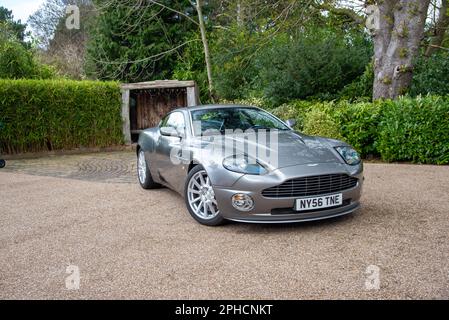 2006 Aston Martin Vantage V8 auf einer Schotterstraße mit Garten und Bäumen dahinter geparkt Stockfoto