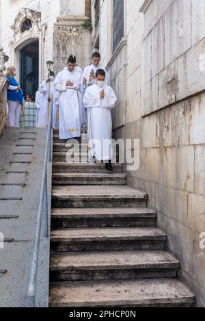 Salvador, Bahia, Brasilien - 08. Dezember 2022: Priester und Seminare steigen die Stufen der Kirche hinab Hunderte von Menschen beten während einer Open-Air-Messe Stockfoto