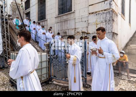 Salvador, Bahia, Brasilien - 08. Dezember 2022: Priester und Seminare steigen die Stufen der Kirche hinab Hunderte von Menschen beten während einer Open-Air-Messe Stockfoto