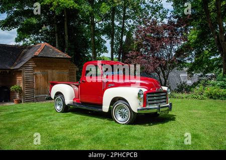 Roter 1949 GMC amerikanischer Pick-up-Truck, der an einem Sommertag auf Gras geparkt ist Stockfoto