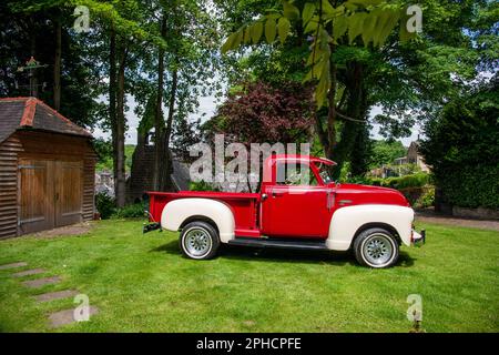 Roter 1949 GMC amerikanischer Pick-up-Truck, der an einem Sommertag auf Gras geparkt ist Stockfoto