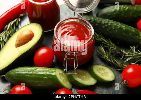 Becher mit leckerem Ketchup und frischem Gemüse auf dem Tisch, Nahaufnahme Stockfoto