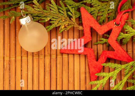 Festlicher roter Stern und mattiertes Glas mit grünen Ästen auf Holzoberfläche Stockfoto