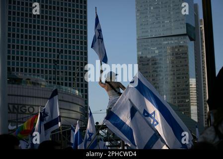 Tel Aviv, Israel. 27. März 2023. Ein Demonstrante mit einer israelischen Nationalflagge protestiert gegen einen Plan zur Überprüfung der Justiz in Tel Aviv, Israel, am 27. März 2023. Der israelische Ministerpräsident Benjamin Netanjahu kündigte am Montagabend an, dass er die Gesetze seines umstrittenen Plans zur Generalüberholung der Justiz des Landes um etwa einen Monat aussetzen werde, um einen "Dialog" zwischen Koalitions- und Oppositionsgesetzgebern zu ermöglichen. Er machte die Bemerkungen in einer Fernsehrede, die kam, nachdem Zehntausende Israelis am Montag vor dem parlament versammelt waren und ein Generalstreik in der Rubrik "T Credit: Xinhua" begann Stockfoto