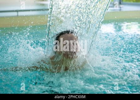 Frauengesicht Entspannen in einem Hydromassage-Pool mit fallendem Wasser in der Schweiz. Stockfoto