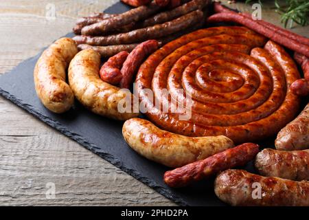 Verschiedene köstliche Würstchen auf einem Holztisch. Auswahl an Biersnacks Stockfoto