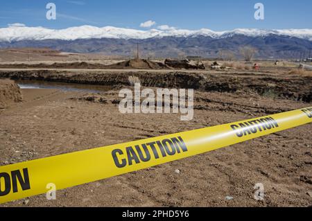 Gelbes Warnband vor einer Wasserspülung auf unbefestigten Straßen Stockfoto