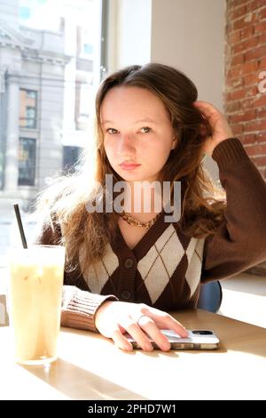 Das Mädchen aus der Nähe trinkt Kaffee. Sie mag morgens Cappuccino oder flach Stockfoto