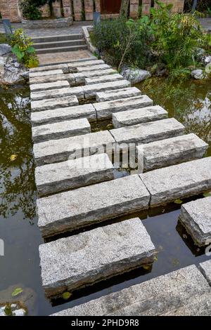 Ein Freizeitspaziergang über einen Teich in einem traditionellen chinesischen Garten Stockfoto