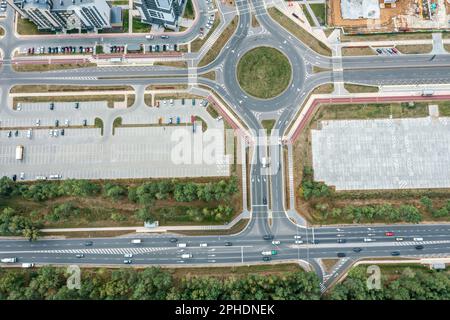 Autobahnkreuzung mit Kreisverkehr und Parkplatz mit geparkten Autos. Draufsicht Stockfoto