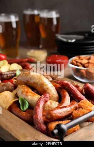 Verschiedene leckere Snacks und Bier auf einem Holztisch, Nahaufnahme Stockfoto