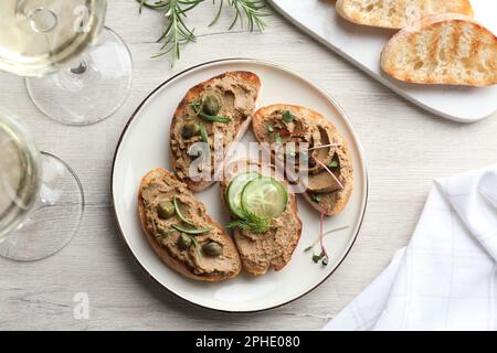 Scheiben Brot mit köstlicher Pastete, serviert auf einem weißen Holztisch, flach liegend Stockfoto