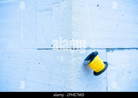 Gelbe Linie eines Ziegelschichtes an einer Wand aus Porenbetonsteinen in Nahaufnahme. Ecke eines frisch gebauten Gasblockhauses. Gefrorene Baustelle Stockfoto