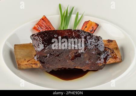 Lang gekochte marinierte Rinderrippen auf einem weißen Porzellanteller Stockfoto