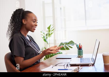 Junge schwarze Ärztin spricht per Ferngespräch mit der Patientin, telemedizinisch Stockfoto