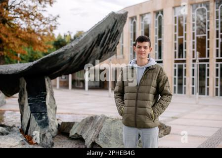 Porträt eines attraktiven Mannes mit legerer Kleidung in Europa. Ein Mann in einer Jacke steht während der Herbstsaison auf der Straße. Portrait oh gutaussehender Teenager gu Stockfoto