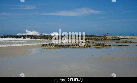 Wellen planschen auf den Felsen und Felsformationen spiegeln sich im nassen Sand am Rainbow Bay Surf Beach, Gold Coast, Queensland, Australien. Stockfoto