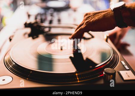 DJ-Hände auf dem Gerätedeck und Mixer mit Schallplatte auf der Party, menschliche Hände mit zwei Vinyl-Drehtisch-Spielern, die nacheinander Lieder spielen. Stockfoto