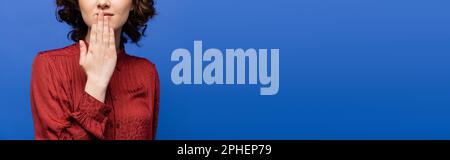 Teilansicht einer jungen Frau in burgunderfarbener Bluse mit Symbol für Dankeschön auf Gebärdensprache isoliert auf blau, Banner, Stockbild Stockfoto