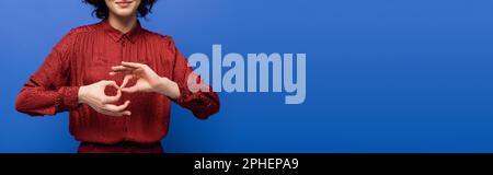 Zugeschnittene Ansicht einer jungen Frau mit Symbol für Dolmetscher auf Zeichensprache isoliert auf blauem Banner, Stockbild Stockfoto