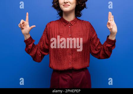 Zugeschnittene Ansicht eines zufriedenen Lehrers mit Buchstaben auf Zeichensprache isoliert auf blauem Stockbild Stockfoto