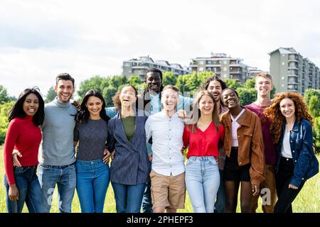 Glückliche Gruppe von multirassischen jungen Freunden, vielfältige Leute, die draußen vor der Kamera lächeln, internationale Gemeinschaft und fröhliche Menschen Stockfoto