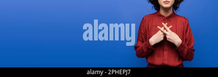 Teilansicht eines Lehrers in roter Bluse mit Geste auf Gebärdensprache isoliert auf blauem Banner, Stockbild Stockfoto