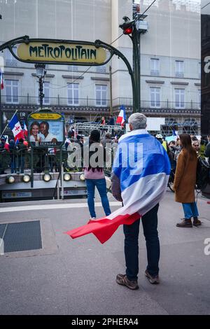 Paris, Frankreich. 25. März 2023. Ein Mann mit französischer Flagge vor einem U-Bahn-Eingang, bei einem Protest gegen die Rentenreform außerhalb des Palais-Roy Stockfoto