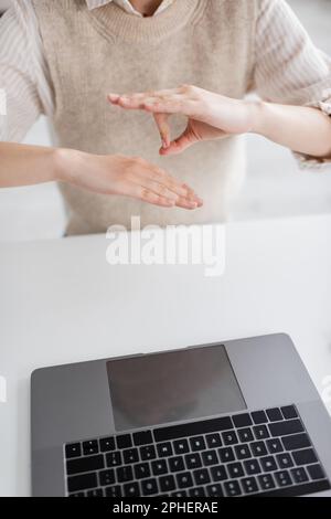 Zugeschnittene Ansicht des Lehrers, die während des Online-Unterrichts eine Geste in der Zeichensprache auf dem Laptop zeigt, Stockbild Stockfoto