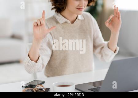 Zugeschnittene Ansicht des Zeichenstimmenlehrers mit alphabetischen Zeichen während des Online-Unterrichts auf einem Laptop zu Hause, Stockbild Stockfoto