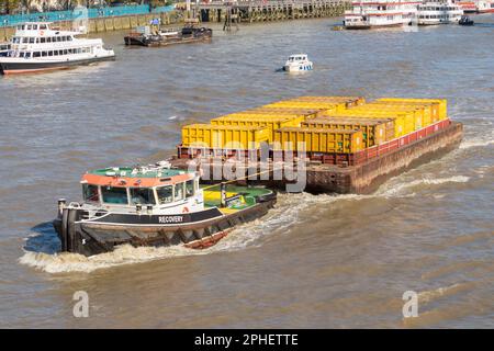 Schleppkahn mit gelben Frachtcontainern entlang der Themse, London, Großbritannien Stockfoto